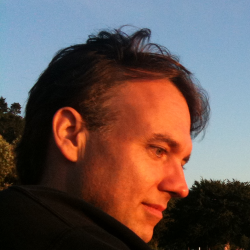 Brent Simmons at Golden Gardens beach, staring at baby unicorns in the sand, that are on fire, at sunset.
